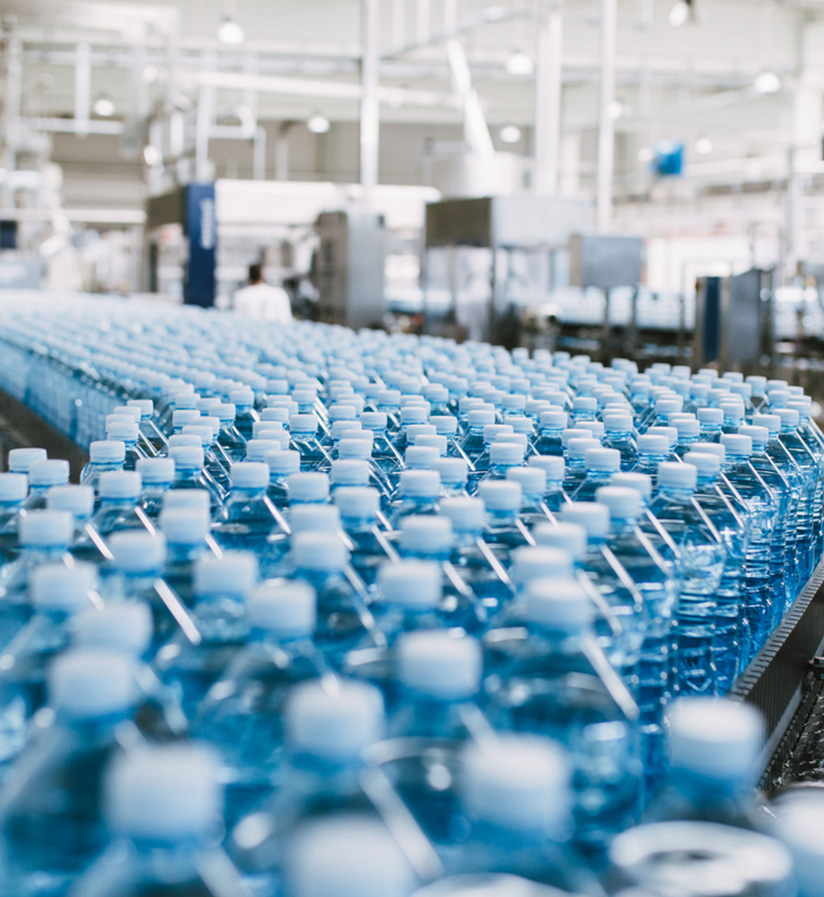 A close up of water bottles on a conveyor belt at a beverage manufacturing plant.