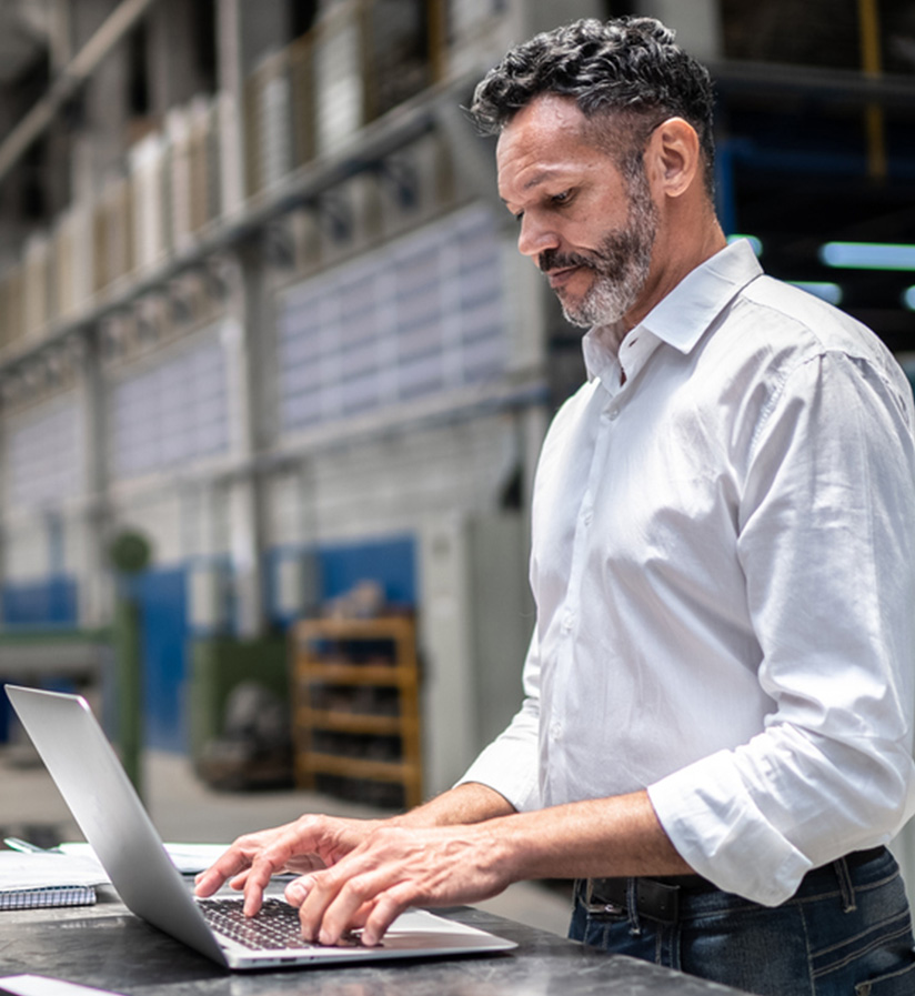 A client working in a factory booking his next shipment on a laptop.