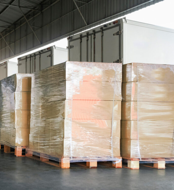 Multiple pallets of packages parked at a loading dock waiting to be loaded onto a semi truck.