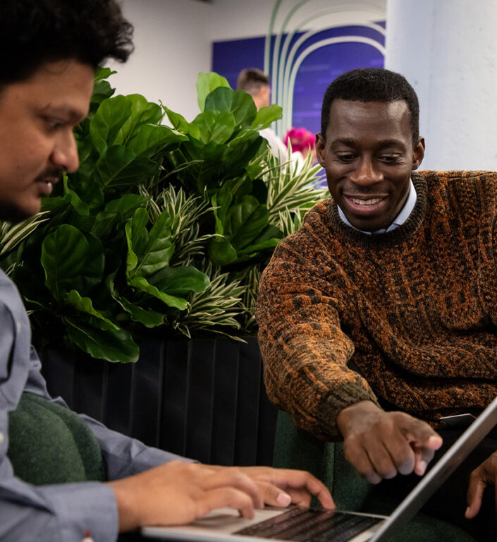 Two Roadtex employees working together on technology projects on a laptop.