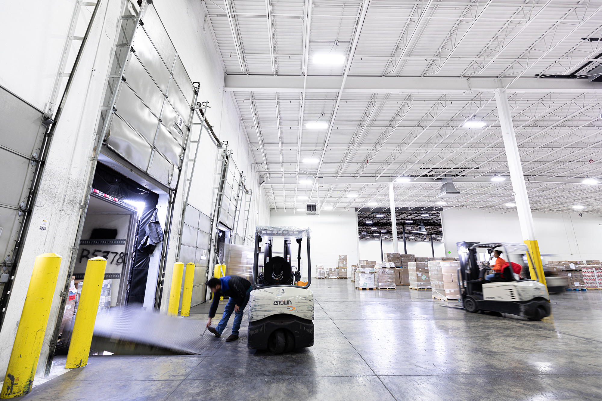 A warehouse employee closing up a truck bed after filling it with freight.