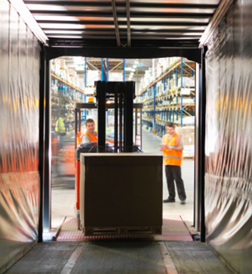 A forklift loading freight from a warehouse onto a semi truck.