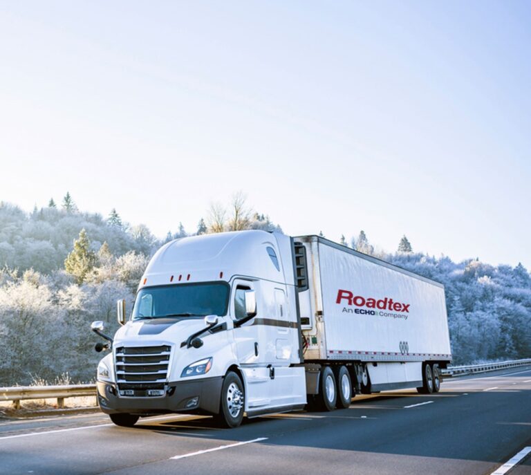 A white semi truck driving down a snowy high way. 